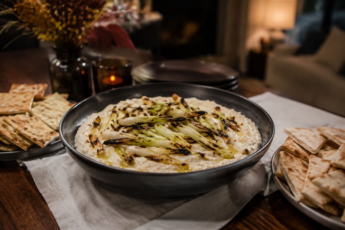Smoky white bean dip with charred scallions, crackers, and pita